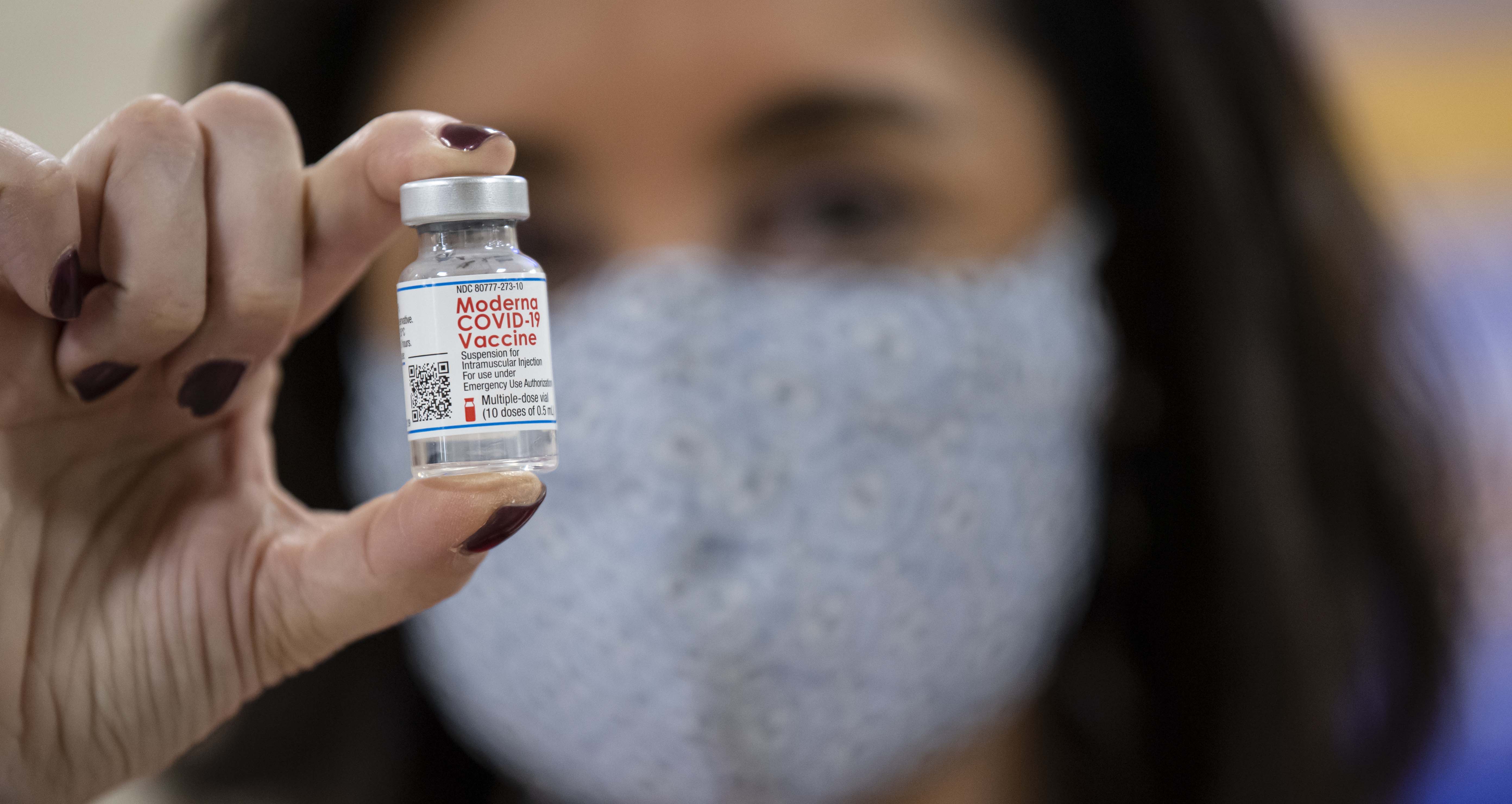 Woman holding vial of Moderna vaccine