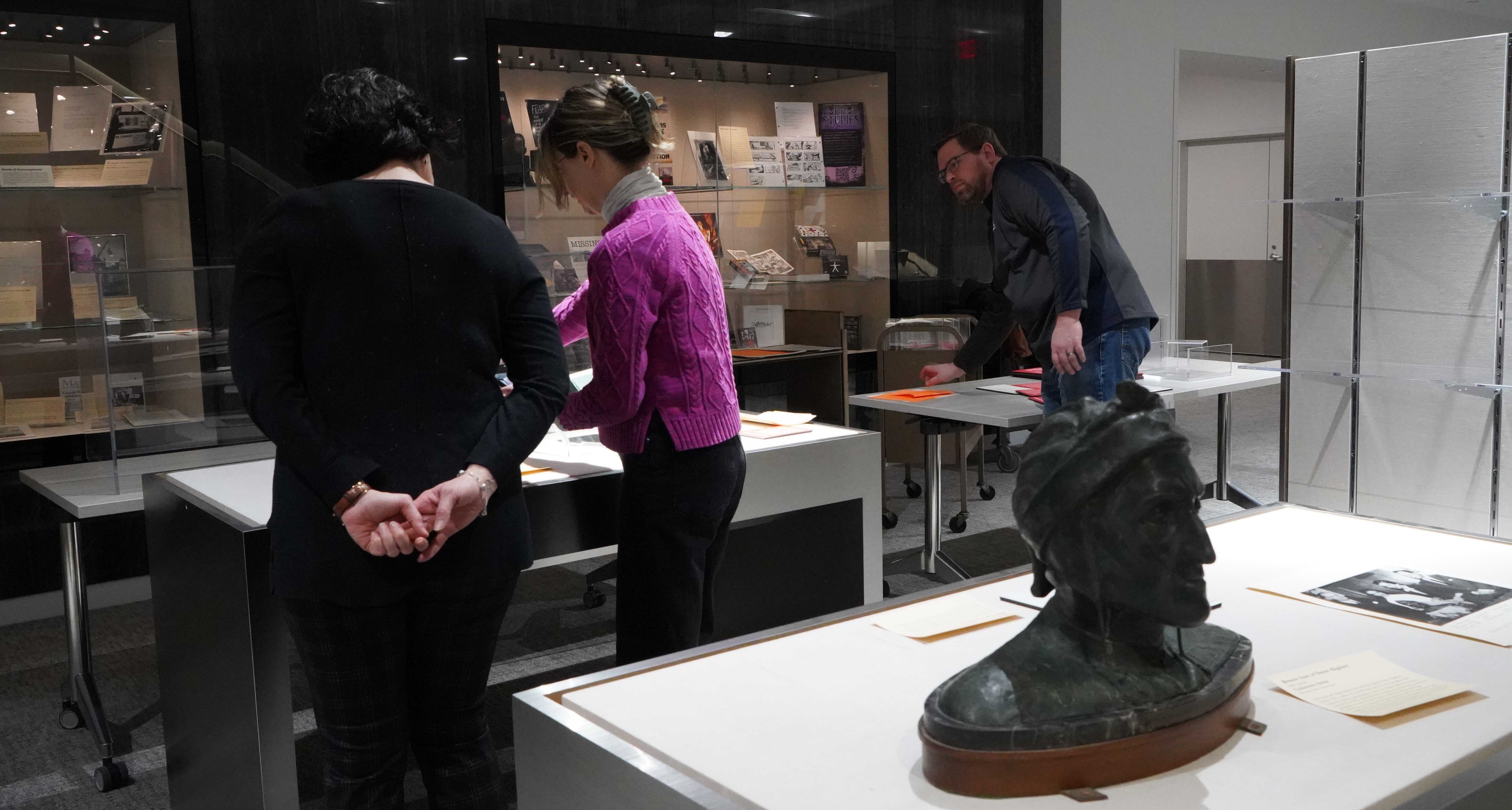 Lina Insana (left), a French and Italian faculty member, gets help from Zachary Brodt, University archivist and records manager, and Megan Massanelli, archives and special collections engagement and outreach librarian at Hillman, to install the exhibit “Read the Room! Uncovering the Italian Room’s Transnational Traces.” (Justin Pastrick | University Library System)