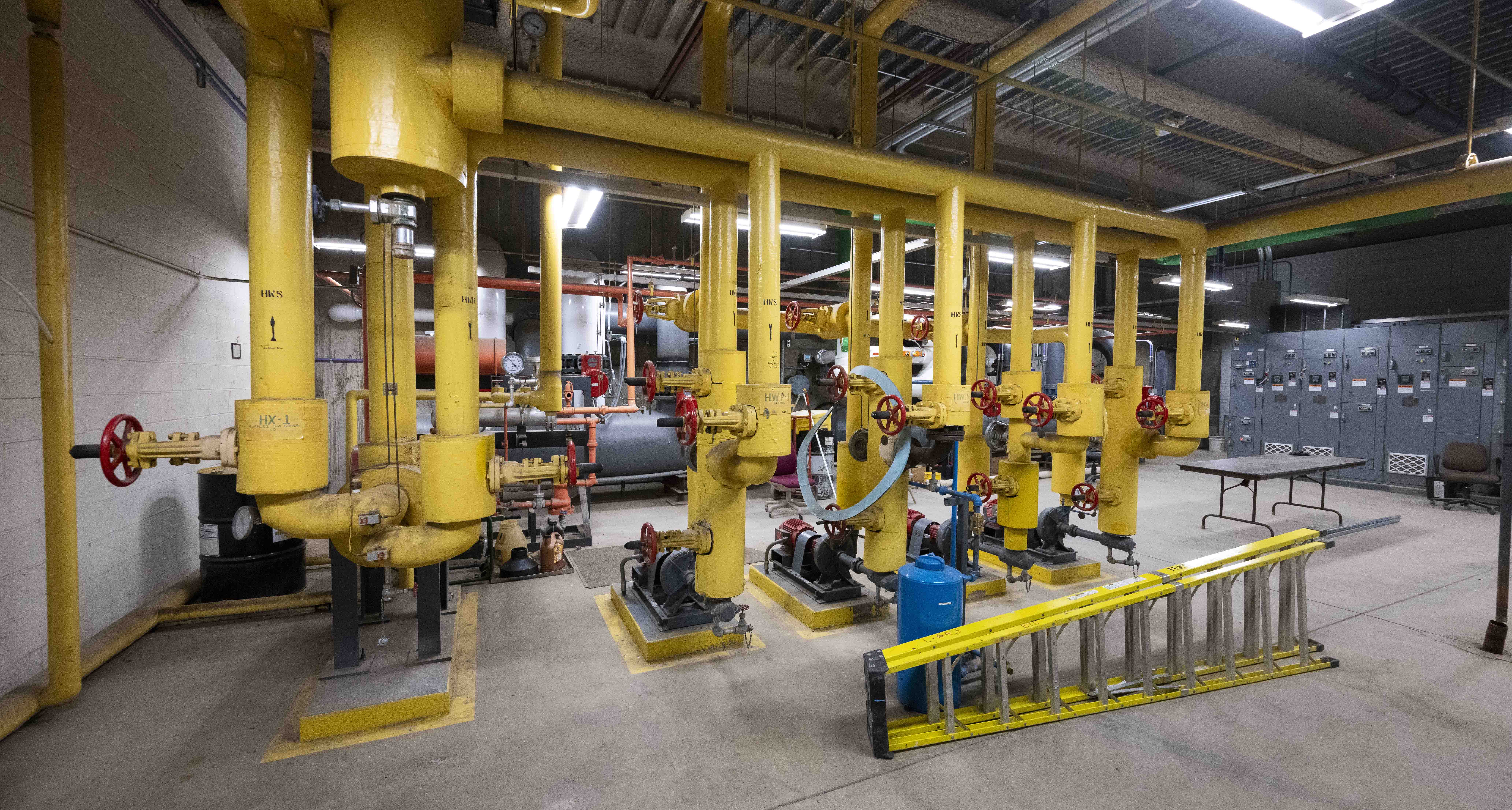 An array of colored pipes converges on floor-mounted pumps in the thermal management system in Posvar Hall, whose 47-year-old chilled-water plant is undergoing an $18.8 million upgrade.