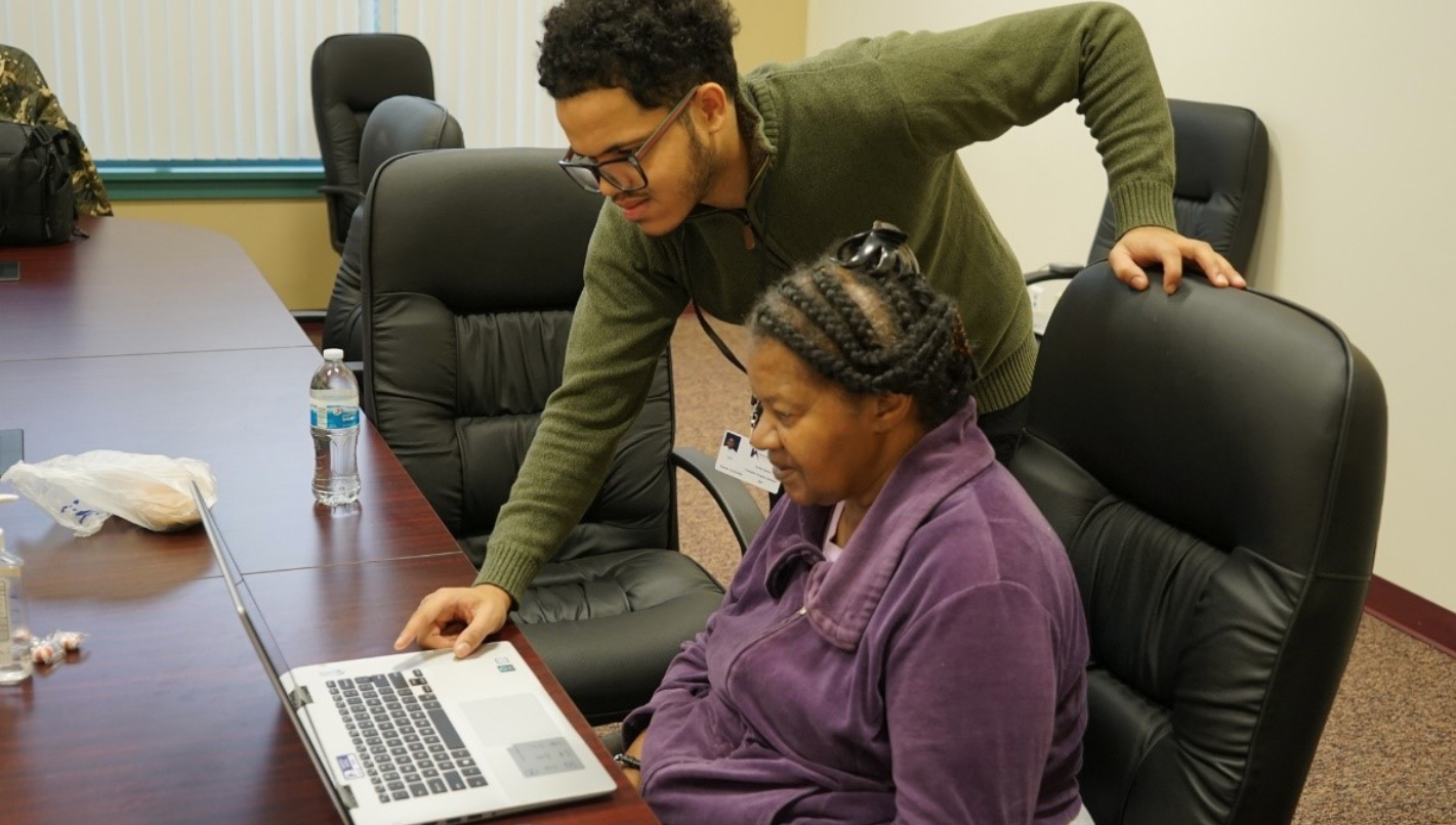 Young. man helping elderly woman on computer