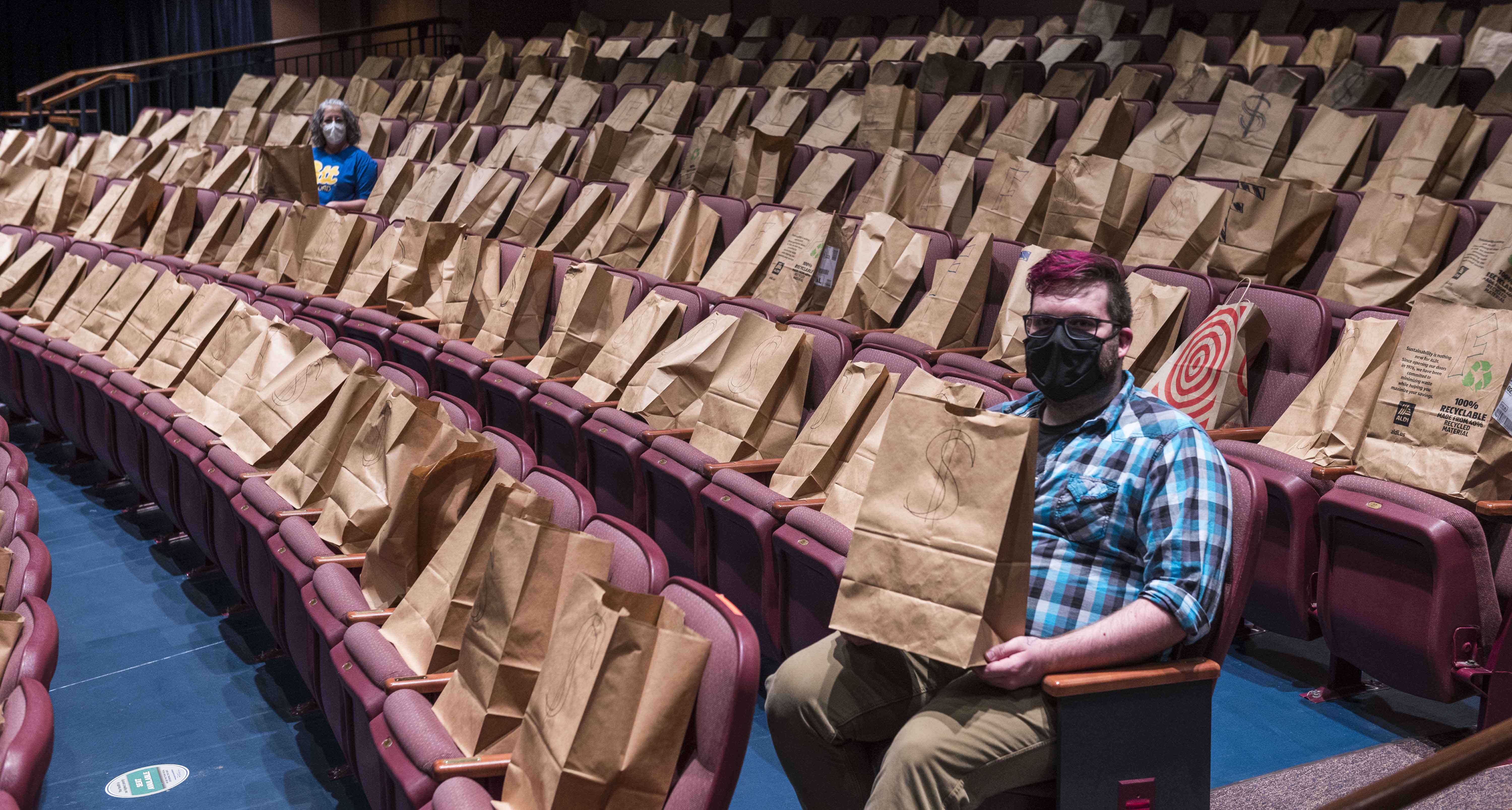 Two people sitting in theater filled with grocery bags